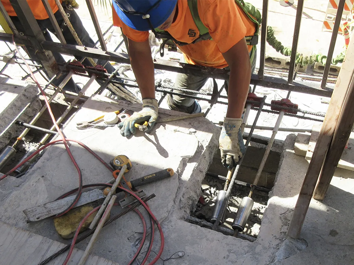 Structural Systems Hawaii technician repairing post-tension cable anchors in concrete slab opening