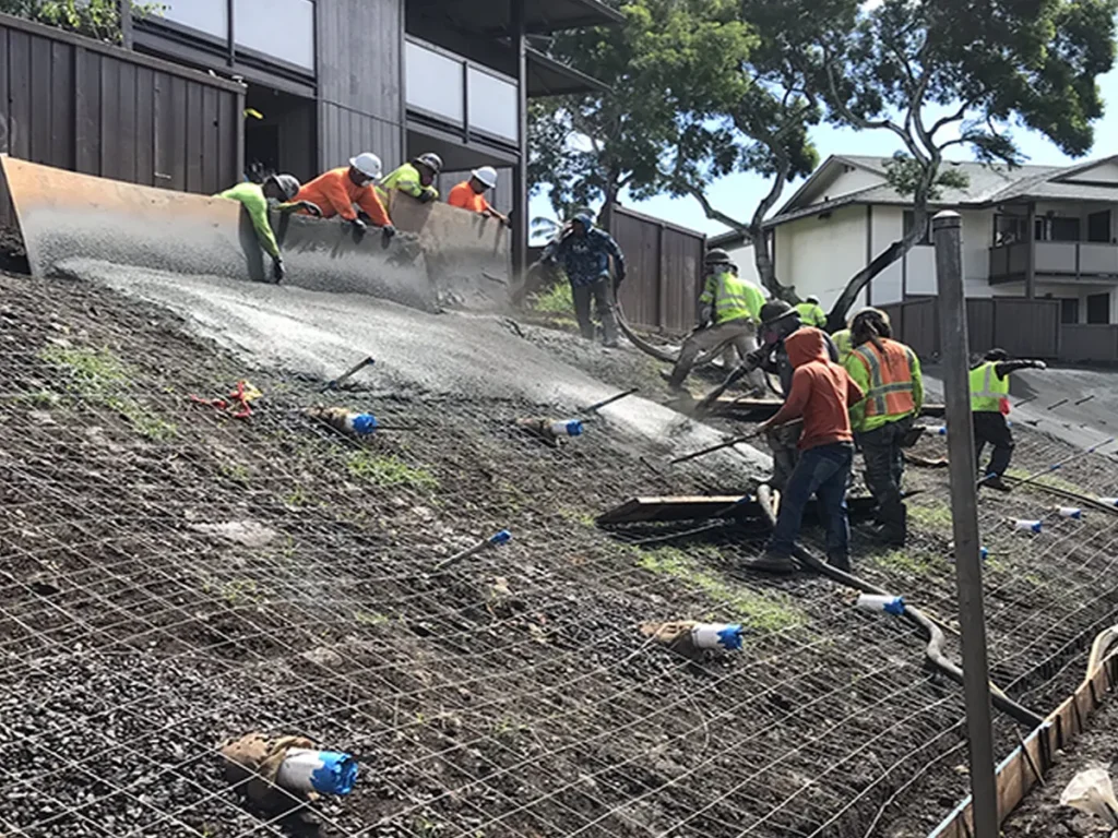 Structural Systems Hawaii crew applying shotcrete over wire mesh for slope stabilization
