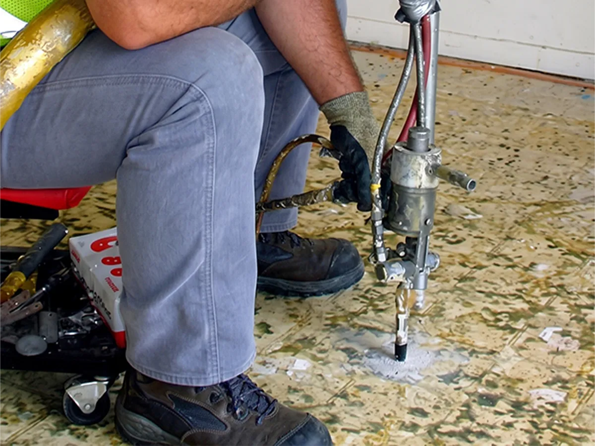 Structural Systems Hawaii technician performing void filling and soil stabilization injection under floor